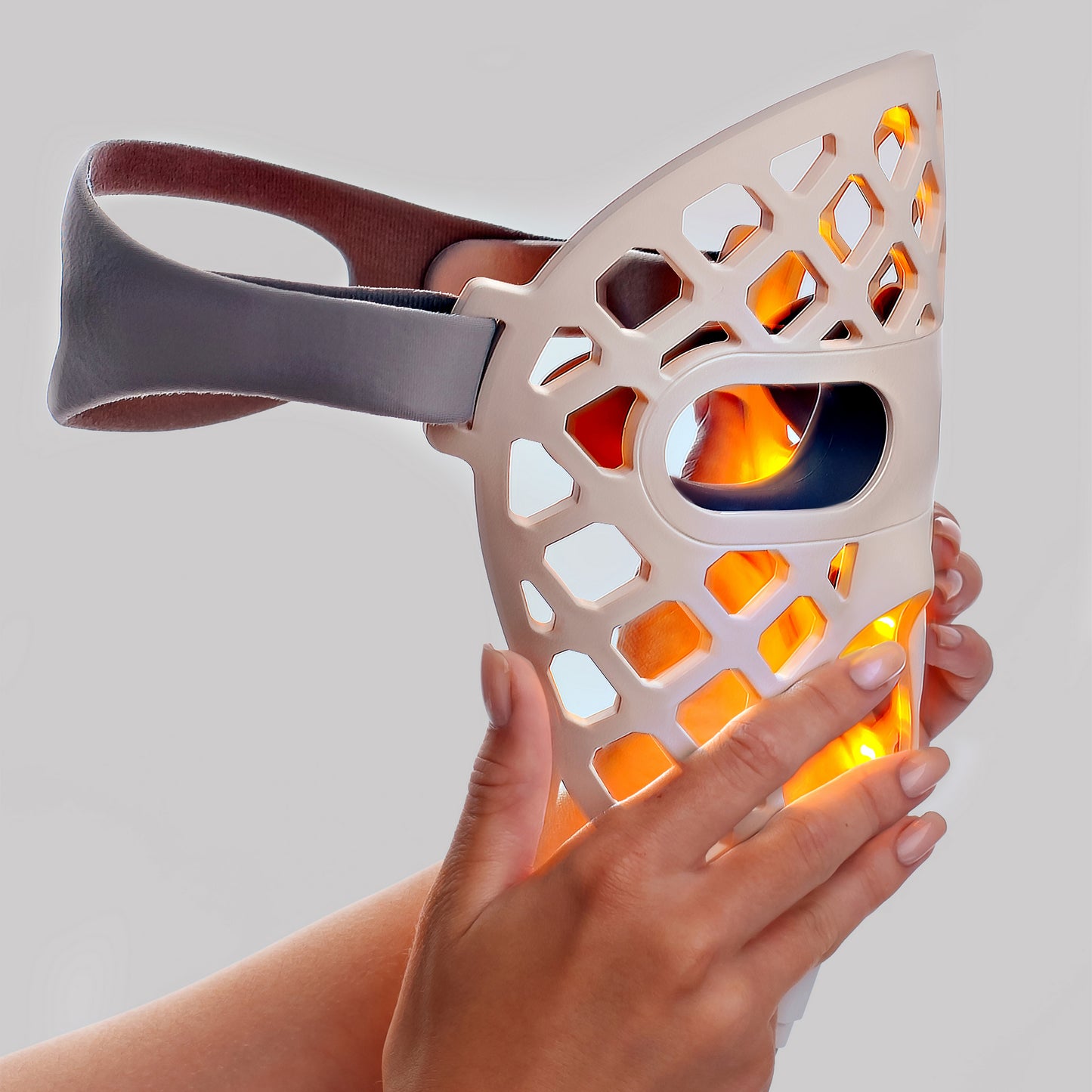 Hand holding the LED face mask with red light